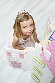 A 5 years old girl dressed like a princess playing with her dollhouse