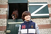 A boy in front of a horse in a stable