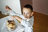 A little boy taking some cookies in a jar