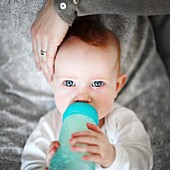 Baby girl drinking from feeding bottle