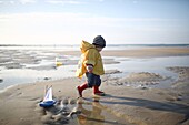 A 1 year old boy plays on the beach