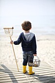 3 years old boy goes fishing with a net at the beach