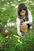 A 5 years old girl picking up Easter eggs in the countryside