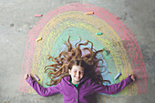 Caucasian girl laying on chalk rainbow