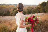 Bride holding bouquet on rural hilltop