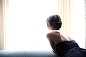 Rear view of woman in evening gown looking out window