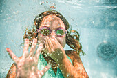 Caucasian girl holding nose underwater in swimming pool