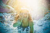 Caucasian girl swimming underwater gesturing peace sign