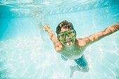 Caucasian boy swimming underwater in swimming pool