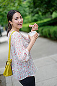 Hispanic woman eating frozen yogurt on city sidewalk