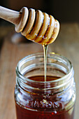 Honey Dripping From Wood Dipper into Jar