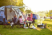Familiencamping, Mutter mit zwei Töchtern draußen beim Grillen am Zelt, Campingplatz, Västervik, Smaland, Schweden