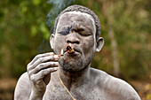 Einheimischer Buschmann bei Rauchzeremonie im Wald, Selous Natur Reservat, Tansania, Afrika