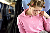 Girl listening to music with earphones in the train, Germany, Europe