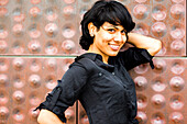 Hispanic woman smiling near metal wall