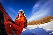 Caucasian woman leaning out car window in snowy field