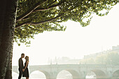 Caucasian couple kissing near bridge, Paris, Ile-de-France, France