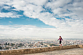 Caucasian woman on wall overlooking scenic view of cityscape, Granada, Spain
