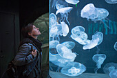 Caucasian woman admiring jellyfish in aquarium