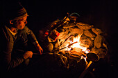 Caucasian man roasting food over campfire