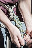 Athlete tying knot on climbing harness