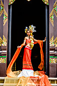 Asian woman standing in ornate temple doorway, Chiang Mai, Chiang Mai, Thailand