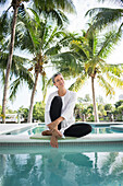 Smiling woman dipping toes in swimming pool