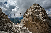 Caucasian hiker crossing rope bridge between rock formations