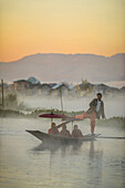 Asian gondolier rowing monks in canoe on river