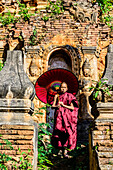 Asian monk-in-training with parasol walking on Buddhist shrine