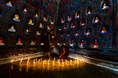 Asian monks-in-training lighting candles in ancient temple