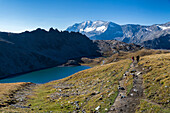 Hikers walking on the Colle del Nivolet beside Rossett Lake (Lago Rossett), Gran Paradiso National Park, Alpi Graie (Graian Alps), Italy, Europe