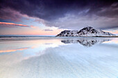 Sunset on Skagsanden beach surrounded by snow covered mountains reflected in the cold sea, Flakstad, Lofoten Islands, Arctic, Norway, Scandinavia, Europe