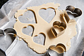 Heart-Shaped Cookie Cutters and Cookie Dough on Wax Paper