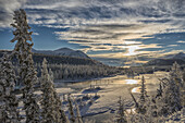 The sun breaks through the clouds above the Takhini River on a late winter afternoon, near Whitehorse, Yukon, Canada