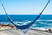 Blue hammock over a wooden dock at the water's edge, Cabo Polonio, Uruguay