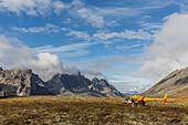 Three men get out of a helicopter on a mountain top in Tombstone Territorial Park, Yukon, Canada