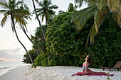 Caucasian woman practicing yoga on tropical beach