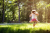 Girl sitting on swing in field