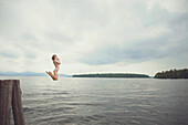 Caucasian girl jumping in remote lake