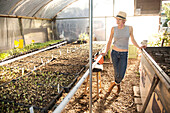 Caucasian farmer admiring plants in greenhouse