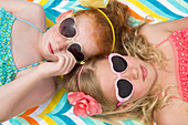 Caucasian girls sunbathing in heart-shaped sunglasses