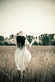 Woman walking in tall grass in rural field