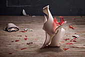 Broken pottery vase on wooden table