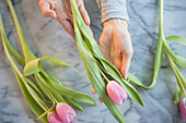 Gemischtrassige Frau hält Tulpen am Tisch