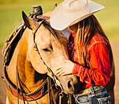 Caucasian cowgirl petting horse on ranch