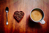 Spoon, beans and cup of coffee on counter