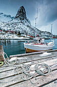A boat moored in the cold sea in the background the snowy peaks, Reine. Lofoten Islands, Northern Norway, Scandinavia, Arctic, Europe