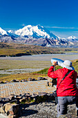 A male visitor views Mt. McKinley through the park provided scope at Eielson Visitor Center in Denali National Park, Interior Alaska, Summer, USA.