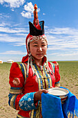 Woman in red deel and pointed hat with silver bowl of milk to welcome visitors, Gobi desert, near Bulgan, Omnogov, Mongolia, Central Asia, Asia
